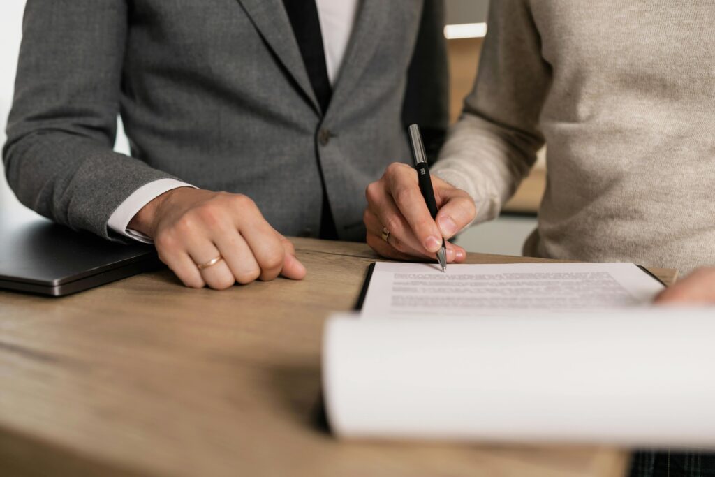 Two professionals reviewing and signing a legal document at a desk